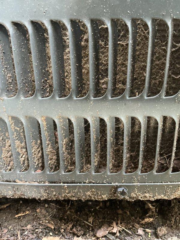 Completed annual cooling maintenance on 6-year-old Goodman air conditioning system. Inspected condenser unit exterior, noting heavy dust and debris accumulation on condenser coil fins requiring cleaning attention, and observed algae growth on concrete pad indicating drainage considerations. Documented unit condition with photos for maintenance records.
