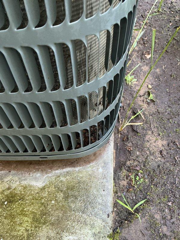 Completed annual cooling maintenance on 6-year-old Goodman air conditioning system. Inspected condenser unit exterior, noting heavy dust and debris accumulation on condenser coil fins requiring cleaning attention, and observed algae growth on concrete pad indicating drainage considerations. Documented unit condition with photos for maintenance records.
