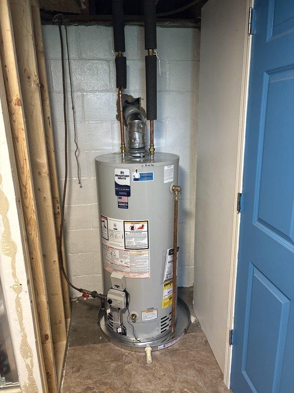 Successfully installed a 40-gallon Bradford White automatic storage natural gas water heater with 40,000 BTU/h input capacity in utility closet alcove. Connected copper water supply lines, installed proper venting with black exhaust piping, and established all necessary valve controls and connections. Unit was properly positioned against concrete block wall with all manufacturer specifications verified, safety labels intact, and operating instructions accessible for future reference.