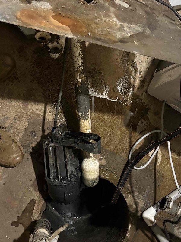 Responded to emergency sump pump failure in basement of 50-year-old residential property that had experienced flooding from laundry drain backup. Upon arrival, found existing sump pump system in severely deteriorated condition with extensive moisture damage, corrosion, and biological growth throughout the sump pit area. Assessed pump functionality, inspected drainage lines and discharge piping, and evaluated overall system condition in utility space showing signs of long-term water exposure and inadequate maintenance. Documented equipment condition and surrounding area with photographic evidence for home warranty claim processing through American Home Shield. Provided homeowner with findings and recommendations for system repair or replacement to prevent future flooding incidents.