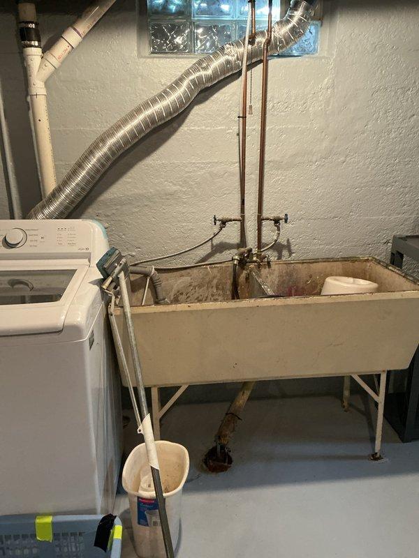 Responded to water leak complaint in basement utility area affecting 13-year-old Ecoair HVAC system. Inspected furnace and air conditioning unit to identify source of water leakage between AC and furnace components. Documented existing conditions of mechanical room including furnace unit, ductwork connections, and utility sink area with photographic evidence for diagnostic purposes.