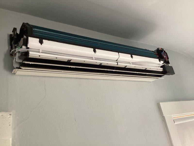 Responded to water leak from newly installed ductless mini-split system that was still operating in heating mode. Upon inspection, opened front cover to access internal components and identified source of water intrusion. Examined drain line connections, evaporator coil assembly, and condensate management system. Documented unit condition with internal components exposed, noting wiring connections and filter assembly. Addressed leak issue to prevent further water damage while maintaining system functionality.