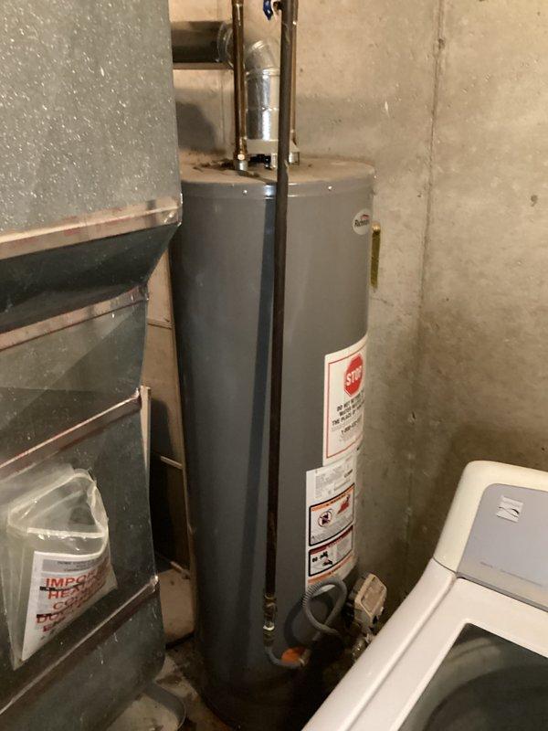 Conducted on-site assessment of existing water heater system in basement utility area of duplex property for replacement estimate. Documented current installation including cylindrical tank-style water heater with standard top connections, relief valve, and flexible connector piping. Evaluated associated plumbing infrastructure including expansion tank, copper and galvanized piping, and shutoff valves to determine scope of replacement work required.