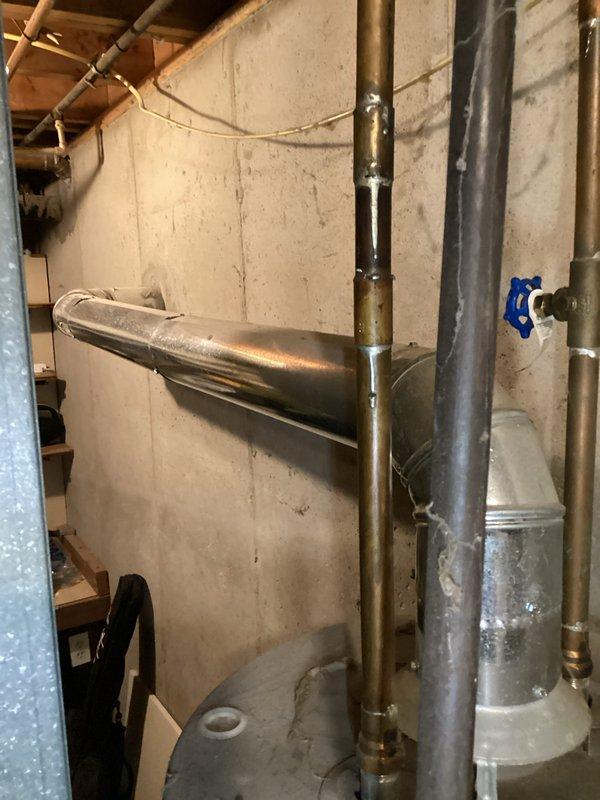 Conducted on-site assessment of existing water heater system in basement utility area of duplex property for replacement estimate. Documented current installation including cylindrical tank-style water heater with standard top connections, relief valve, and flexible connector piping. Evaluated associated plumbing infrastructure including expansion tank, copper and galvanized piping, and shutoff valves to determine scope of replacement work required.