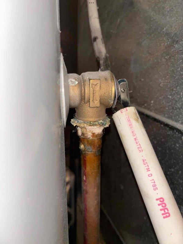 Responded to emergency plumbing leak in basement where burst pipe was actively leaking in multiple locations onto carpeted flooring. Primary leak source identified at water filter canister assembly with compromised brass elbow fitting connecting aged copper supply line to newer PEX piping. Shut off water supply to stop active flooding, assessed extent of damage to affected areas, and documented corroded copper pipe connections and deteriorated brass fittings requiring replacement. Photographed plumbing assembly showing transition point between old copper and modern PEX materials, along with HVAC components and structural elements in vicinity of leak. Provided immediate leak mitigation to prevent further water damage to basement carpet and surrounding areas.