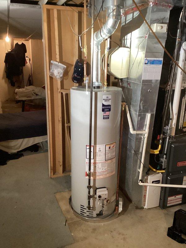 Completed installation of automatic storage water heater with new copper piping connections in basement mechanical room. Unit was properly positioned, connected to existing gas and water lines with appropriate brass fittings, and tested for proper operation alongside existing HVAC furnace system.