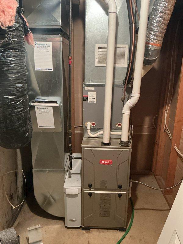 Responded to service call for leaking water heater approximately 10 years old. Upon arrival, performed visual inspection of water heater and surrounding plumbing connections in basement utility area. Identified source of leak at water heater tank or associated piping. Documented existing HVAC system installation including Bryant furnace, air handler, and ductwork configuration. Photographed water heater piping assembly showing copper supply lines with shut-off valves, galvanized vent ductwork, and connection points. Assessed overall condition of unit and determined age-related failure requiring replacement recommendation. Provided customer with diagnostic findings and repair options for resolution of active water leak.