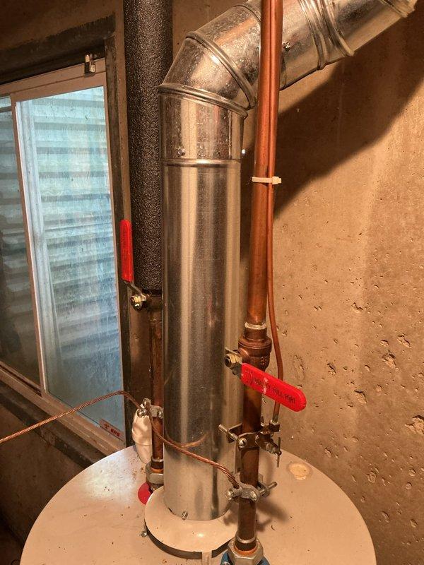 Responded to service call for leaking water heater approximately 10 years old. Upon arrival, performed visual inspection of water heater and surrounding plumbing connections in basement utility area. Identified source of leak at water heater tank or associated piping. Documented existing HVAC system installation including Bryant furnace, air handler, and ductwork configuration. Photographed water heater piping assembly showing copper supply lines with shut-off valves, galvanized vent ductwork, and connection points. Assessed overall condition of unit and determined age-related failure requiring replacement recommendation. Provided customer with diagnostic findings and repair options for resolution of active water leak.