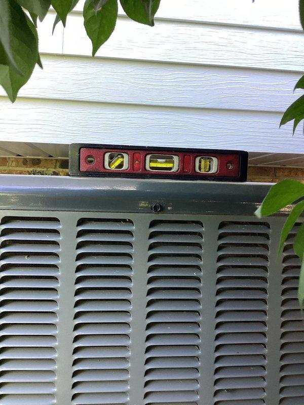 Leveled exterior condenser unit using landscaping materials to ensure proper positioning and operation. Unit was assessed for plumb and level conditions, with adjustments made to stabilize the equipment on its pad. Work completed under warranty coverage.