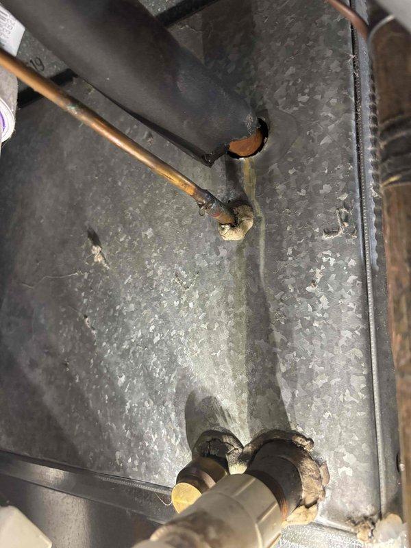 Responded to water leak complaint originating from furnace area during air conditioner operation on 7-year-old EnergiAir system. Upon inspection, identified condensate drain issue within the air handler unit. Examined internal components including copper refrigerant lines, condensate drain connections, and associated plumbing fittings. Found compromised condensate drain line connection with deteriorated sealing at the drain pan outlet. Documented existing conditions showing aged pipe fittings and wear on mechanical housing components. Cleared blockage from condensate system and verified proper drainage flow. Tested system operation to confirm leak resolution and proper condensate evacuation during cooling cycle.