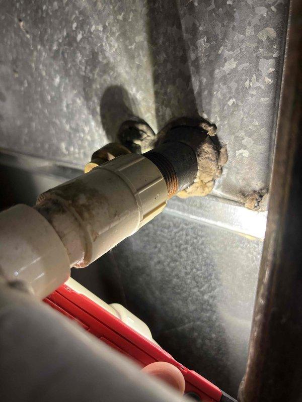 Responded to water leak complaint originating from furnace area during air conditioner operation on 7-year-old EnergiAir system. Upon inspection, identified condensate drain issue within the air handler unit. Examined internal components including copper refrigerant lines, condensate drain connections, and associated plumbing fittings. Found compromised condensate drain line connection with deteriorated sealing at the drain pan outlet. Documented existing conditions showing aged pipe fittings and wear on mechanical housing components. Cleared blockage from condensate system and verified proper drainage flow. Tested system operation to confirm leak resolution and proper condensate evacuation during cooling cycle.