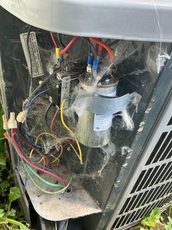 Completed annual cooling maintenance on 20-year-old American Standard air conditioning system. Performed comprehensive inspection of outdoor condensing unit, noting significant dirt accumulation and weathering on internal components consistent with age and outdoor exposure. Inspected dual-run capacitor and all electrical connections including multiple wire terminals and wire nuts; all connections found secure. Examined indoor air handler unit in basement utility space, which showed evidence of recent flood damage with visible dust and debris accumulation on surrounding surfaces and concrete flooring. Verified proper operation of all major components including compressor, condenser fan motor, and blower assembly. System currently operating within normal parameters despite age of equipment.