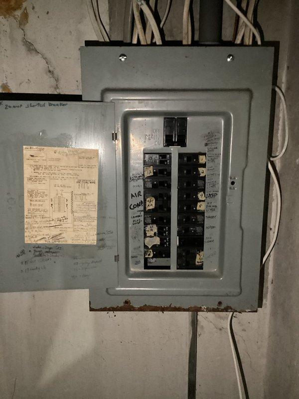 Completed electrical club inspection of Murray/Crouse-Hinds main service panel in basement utility area. Documented existing conditions including significant rust corrosion along bottom edge of panel enclosure indicating moisture intrusion, deteriorated paint on panel door, aging circuit breaker configuration with dual vertical rows, and multiple handwritten markings on equipment surfaces. Photographed all electrical connections, conduit entries at top and bottom of panel, adjacent junction box with posted documentation, and overall panel installation for compliance review and future reference.