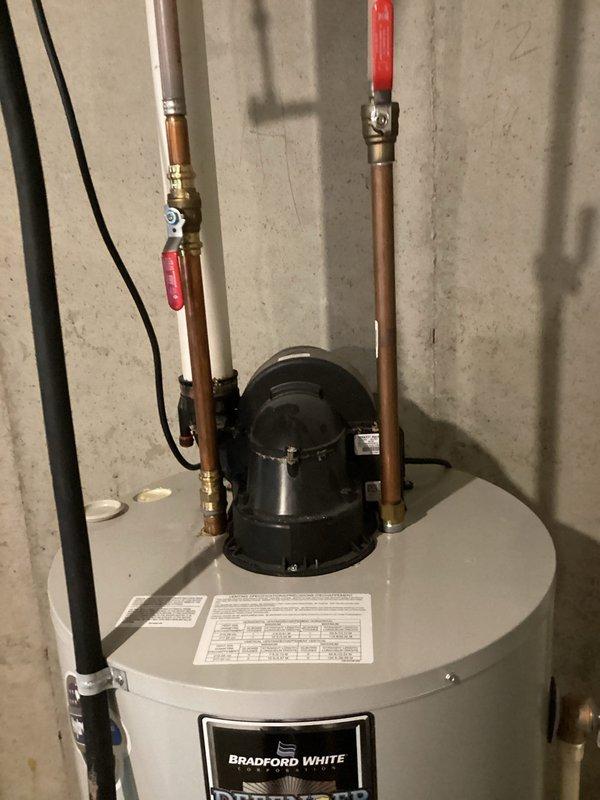 Responded to water heater leak with continuous dripping into drain pan and customer complaint of odor in water supply. Removed anode rod from Bradford White water heater to address odor issue, as magnesium anode rods can react with water chemistry causing sulfur smell. Inspected circulation pump, copper piping, and valve connections for integrity and proper operation. Documented installation condition with photographs showing pump assembly, piping configuration, and valve placement for service records.