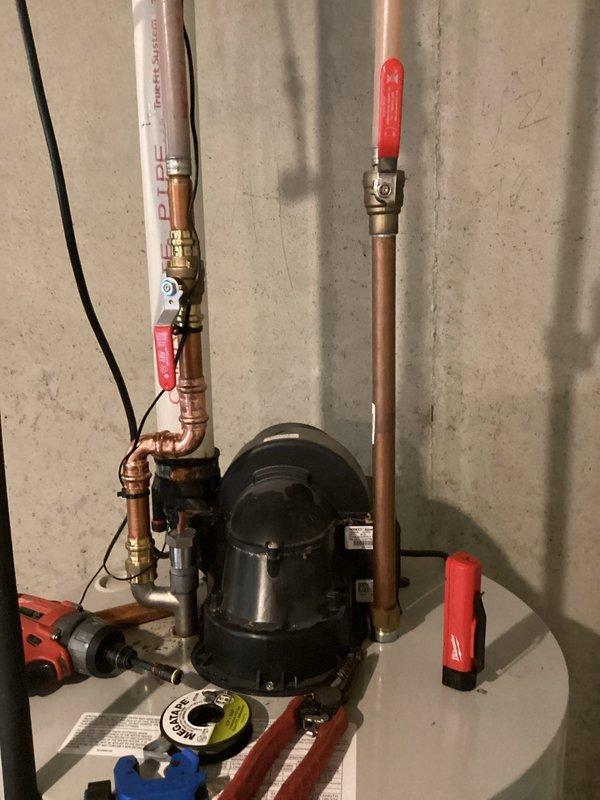 Responded to water heater leak with continuous dripping into drain pan and customer complaint of odor in water supply. Removed anode rod from Bradford White water heater to address odor issue, as magnesium anode rods can react with water chemistry causing sulfur smell. Inspected circulation pump, copper piping, and valve connections for integrity and proper operation. Documented installation condition with photographs showing pump assembly, piping configuration, and valve placement for service records.