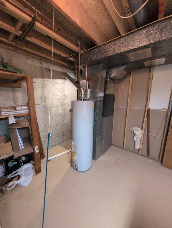Completed full AC system installation in residential basement utility room. New HVAC unit installed adjacent to existing water heater with proper clearances maintained. Connected refrigerant lines, electrical service, condensate drain via PVC piping, and integrated supply/return ductwork to existing distribution system. System tested, charged to manufacturer specifications, and verified operational. Payment arrangements updated per customer request with post-dated check collected.