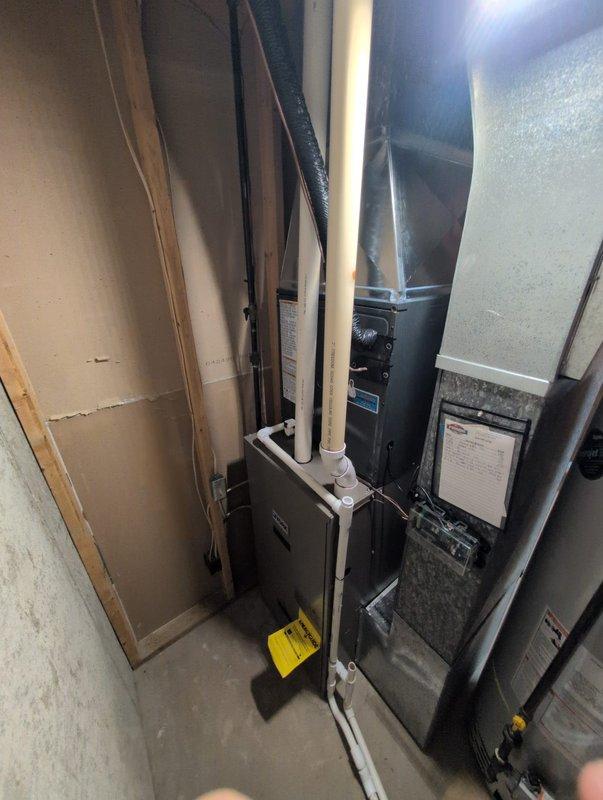 Completed full AC system installation in residential basement utility room. New HVAC unit installed adjacent to existing water heater with proper clearances maintained. Connected refrigerant lines, electrical service, condensate drain via PVC piping, and integrated supply/return ductwork to existing distribution system. System tested, charged to manufacturer specifications, and verified operational. Payment arrangements updated per customer request with post-dated check collected.