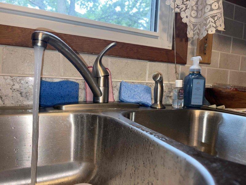 Responded to kitchen sink leak complaint. Upon arrival, inspected double-basin stainless steel sink with modern faucet assembly and spray nozzle attachment. Examined visible moisture and water droplets on sink surface. Accessed cabinet beneath sink to evaluate plumbing system, including white PVC drain assemblies, P-trap configuration, and braided stainless steel supply lines. Inspected metal drain baskets, threaded tailpieces, and slip joint connections for signs of leakage or deterioration. Documented existing plumbing configuration with photographs for service records. All accessible plumbing components assessed for proper function and potential leak sources.