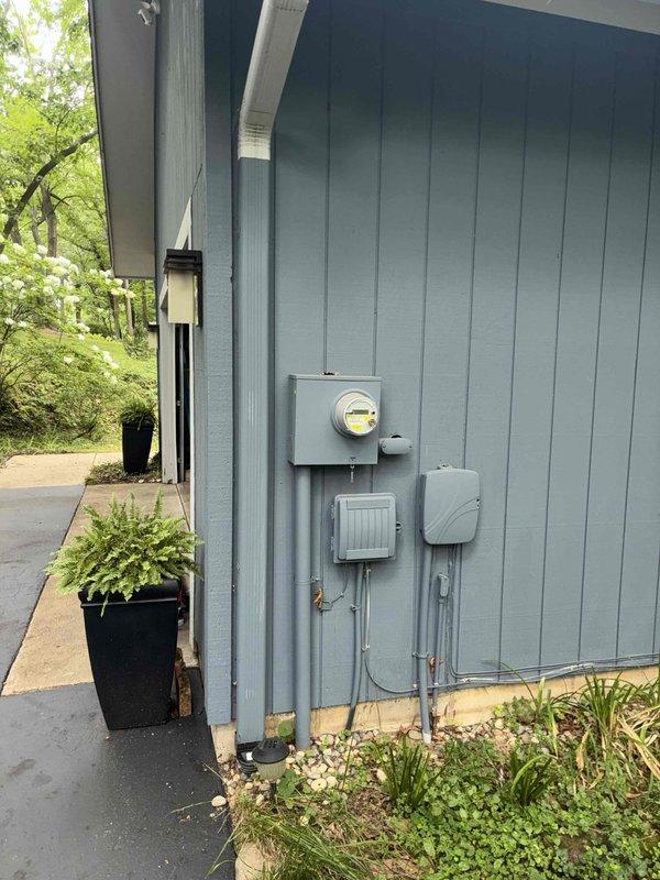 Conducted on-site evaluation for new Generac generator installation at 45-year-old single-family residence. Assessed existing electrical service configuration, including meter location, electrical panels, and available mounting space on exterior wall with blue-gray vertical siding. Documented current utility setup featuring digital electric meter, junction boxes, and conduit routing to determine optimal generator placement and transfer switch installation requirements. Photographed electrical infrastructure and potential installation area to develop comprehensive estimate for whole-home standby generator system.