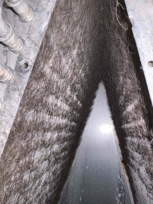 Responded to service call for non-operational 11-year-old EnergiAir humidifier system installed in 2019. Upon inspection, performed diagnostic testing using calibrated pressure gauge and digital multimeter to assess system functionality and electrical continuity. Documentation photos captured existing ductwork insulation condition showing significant deterioration and equipment testing measurements, with multimeter reading 0.184 during diagnostic procedures.