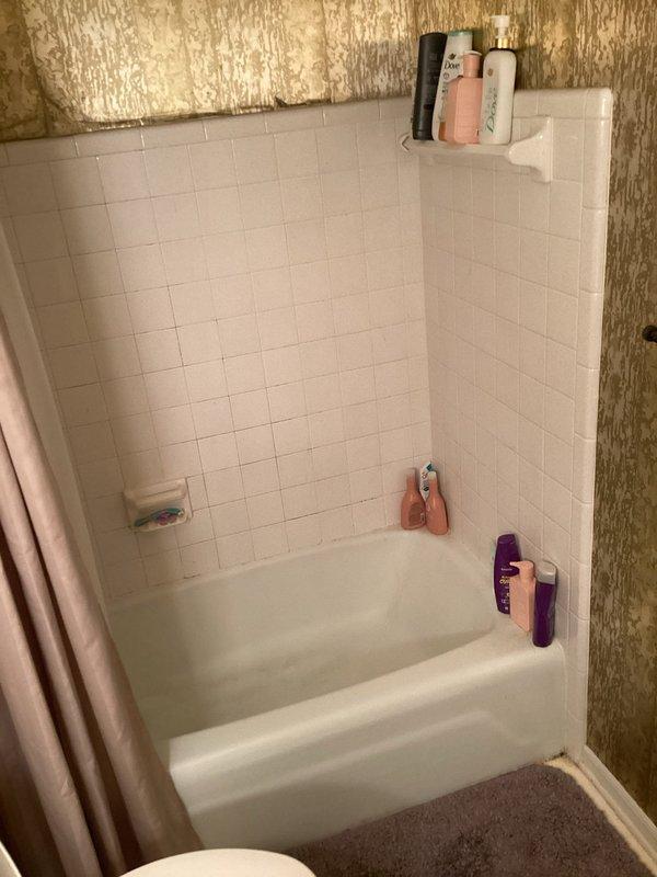 Conducted on-site assessment for tub-shower replacement in residential bathroom. Evaluated existing white tile surround with beige tub unit and documented current conditions including wall finishes, plumbing fixture placement, and exposed insulation above tile line indicating potential scope for complete enclosure renovation. Provided comprehensive estimate for new tub-shower installation.