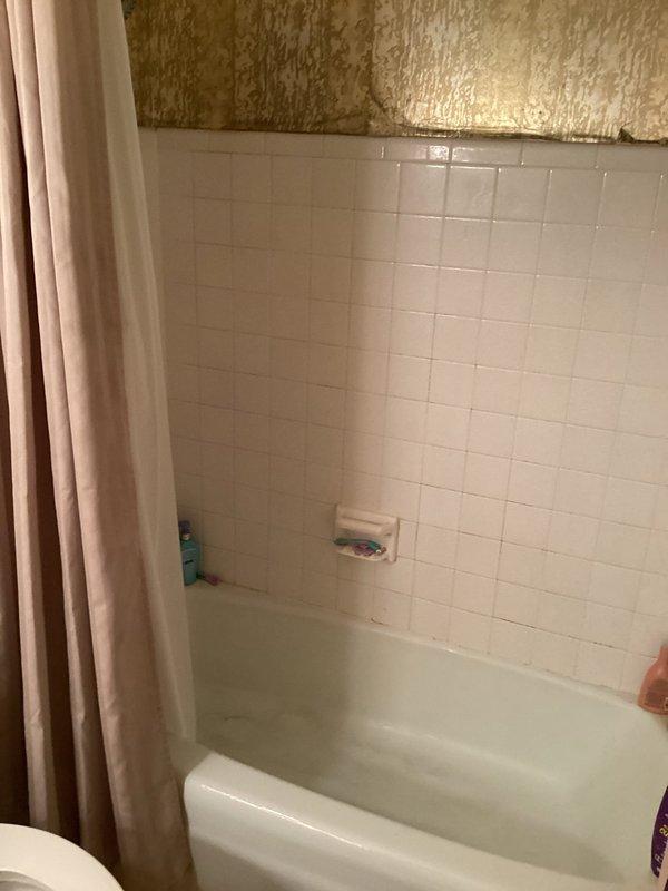 Conducted on-site assessment for tub-shower replacement in residential bathroom. Evaluated existing white tile surround with beige tub unit and documented current conditions including wall finishes, plumbing fixture placement, and exposed insulation above tile line indicating potential scope for complete enclosure renovation. Provided comprehensive estimate for new tub-shower installation.