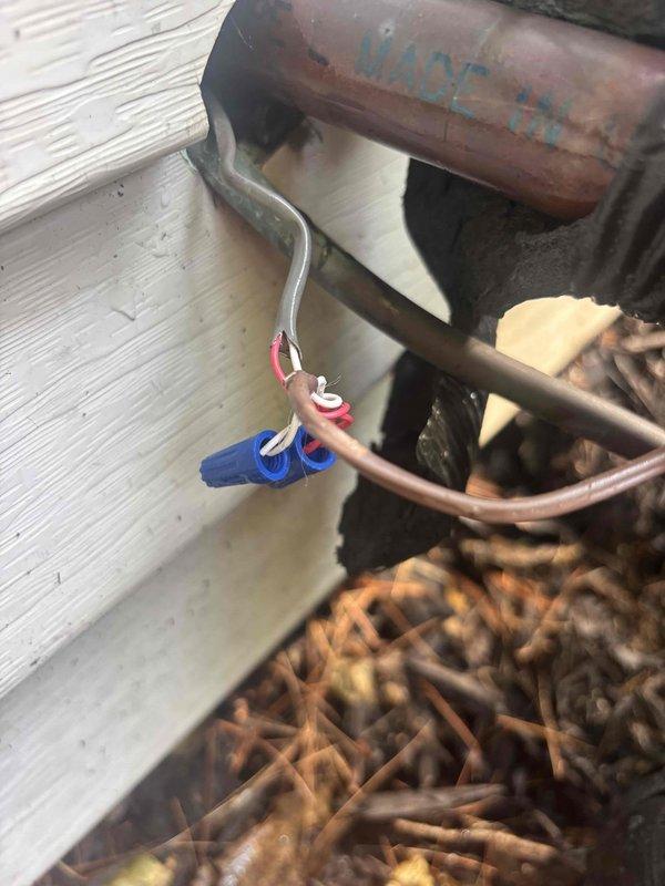 Responded to service call for HVAC unit producing loud noise during operation. Upon inspection, discovered severely deteriorated flex conduit and significant debris accumulation around outdoor unit components. The corrugated rubber hose showed advanced wear and surface degradation, while copper refrigerant lines displayed normal oxidation patina. Found extensive organic debris including dried plant material, twigs, and mulch accumulated in equipment base, restricting airflow and contributing to operational noise. Electrical connections with wire nuts were inspected and found secure. Removed debris buildup from unit base and surrounding area. Documented equipment condition with photographs showing weathered components and rust on metal housing. Unit cooling function confirmed operational with no refrigerant issues detected. Recommended replacement of deteriorated flex conduit to prevent future problems and advised regular debris removal to maintain proper airflow and quiet operation.