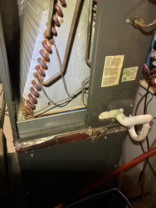 # Drain Pan Replacement

Replaced heavily corroded condensate drain pan on indoor HVAC evaporator coil unit. The existing white metal drip pan exhibited extensive rust deterioration along edges and bottom surfaces, compromising its integrity and creating potential for water damage. Removed old pan from beneath copper coil assembly and installed new replacement pan. Verified proper drainage through existing PVC condensate line. Inspected copper coil condition and electrical connections during service. Tested system operation to confirm proper condensate collection and drainage function. Unit returned to normal operation with no leaks detected.
