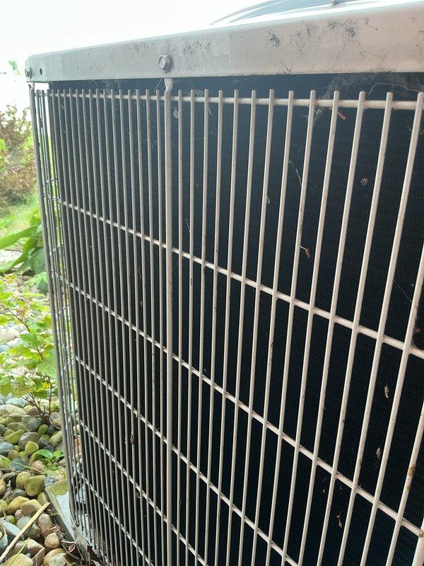 Completed annual cooling maintenance on 12-year-old Carrier condenser unit. Unit exterior showed significant debris accumulation with dried leaves, twigs, and organic matter lodged in protective grille and surrounding condenser fins. Removed all debris from grille guards and coil surfaces. Cleaned condenser coils and exterior cabinet which displayed weathering, discoloration, and environmental staining from outdoor exposure. Performed standard tune-up procedures and verified system operational status.