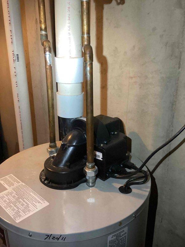 Responded to call for leaking 15-year-old tank water heater in basement with water observed leaking from bottom of unit. Upon inspection, confirmed active leak from base of tank indicating internal tank failure, consistent with age and expected service life of residential water heater installed in 2011. Documented existing installation including plumbing connections, electrical wiring, condensate pump assembly, and PVC venting configuration. Provided estimate for complete water heater replacement including removal and disposal of failed unit, installation of new tank water heater with appropriate venting, and reconnection of all water supply lines and electrical components to restore domestic hot water service.