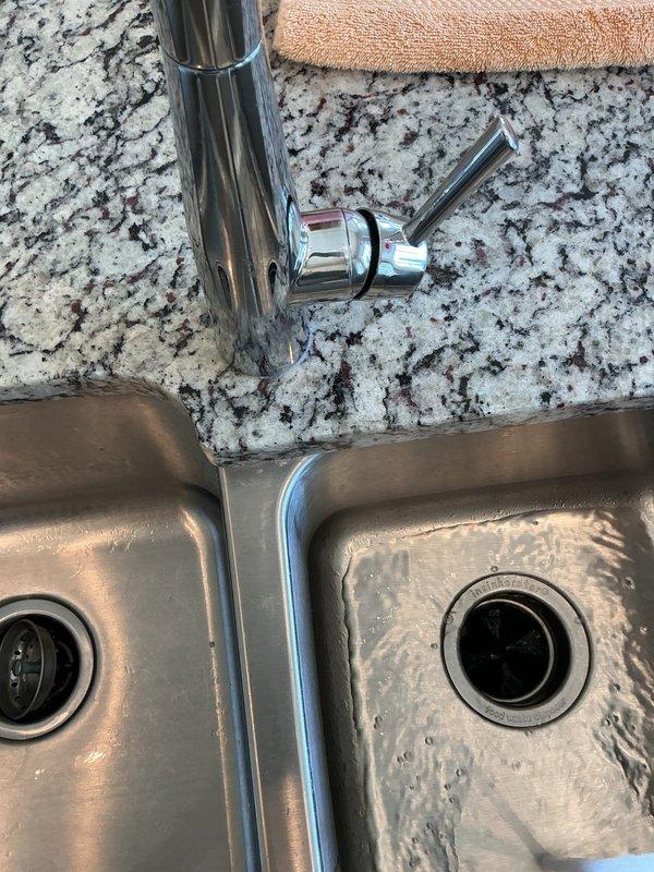 Responded to plumbing leak in kitchen sink area. Upon inspection, identified leak source at sink drain connections and addressed water intrusion issue. Inspected garbage disposal mounting assembly, drain piping, and supply line connections under double-basin stainless steel sink. Tightened mounting hardware, verified proper seal at disposal unit connection, and confirmed all PVC drain lines and copper supply lines were secure with no active leaks. Additionally, installed new faucet fixture in laundry room as requested. Tested both kitchen and laundry installations for proper operation and verified no water leaks present upon completion.