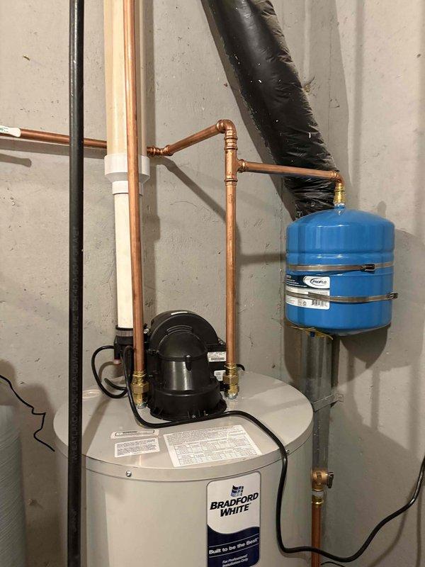 Completed installation of comprehensive residential water treatment and heating system in basement utility area. Installed 50-gallon Bradford White water heater with recirculation pump, Amtrol expansion tank, and proper copper piping connections. Integrated water softener system with black resin tank and beige whole-home filtration system featuring digital control head. All components professionally plumbed with copper supply lines, proper drainage, electrical connections established, and system tested for optimal operation.