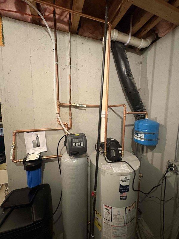 Completed installation of comprehensive residential water treatment and heating system in basement utility area. Installed 50-gallon Bradford White water heater with recirculation pump, Amtrol expansion tank, and proper copper piping connections. Integrated water softener system with black resin tank and beige whole-home filtration system featuring digital control head. All components professionally plumbed with copper supply lines, proper drainage, electrical connections established, and system tested for optimal operation.