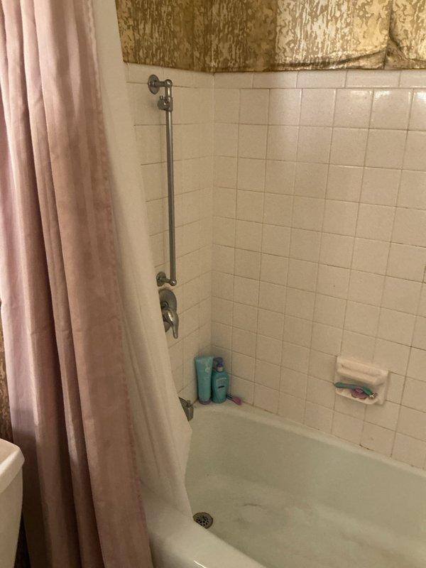 Conducted on-site assessment for tub-shower replacement estimate. Documented existing bathroom configuration featuring standard white bathtub with ceramic tile surround, chrome fixtures including grab bar and shower valve, and built-in soap dish. Photographed current installation to provide accurate quote for new tub-shower unit replacement.
