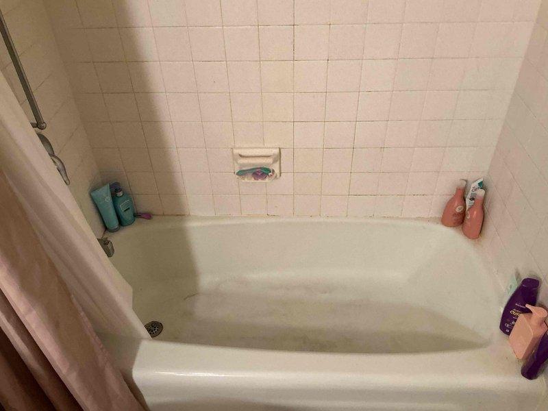 Completed on-site assessment for tub-shower replacement estimate. Existing bathroom features standard alcove-style white bathtub with surrounding tile work showing age-related deterioration. Upper wall surfaces above tile line exhibit significant water damage, discoloration, and suspected mold growth requiring remediation. Lower subway tile section remains structurally intact. Documented current fixtures including chrome shower head, grab bar, and controls. Photographed existing conditions to provide comprehensive quote for complete tub-shower unit replacement and wall surface restoration.
