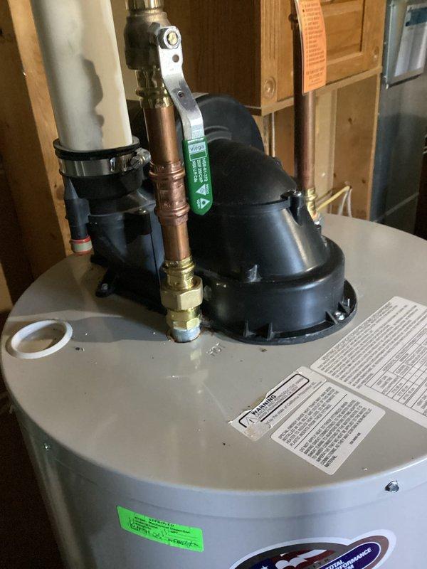 Responded to inspection request for rusting connection on recently installed standard tank water heater. Upon arrival, performed thorough visual inspection of the water heater and associated plumbing connections. Identified significant corrosion and oxidation on copper pipe threaded connection at hot water circulation pump interface, with heavy greenish-brown patina and mineral deposit buildup at the joint where copper pipe meets white plastic fitting. Documented the deteriorated connection showing crusty buildup and severe oxidation at the threaded joint area. Photographed all affected components including the black circulation pump system, corroded copper piping, and overall water heater installation for warranty documentation and follow-up with original installer. Inspection revealed corrosion isolated to specific connection point on hot water side of system.