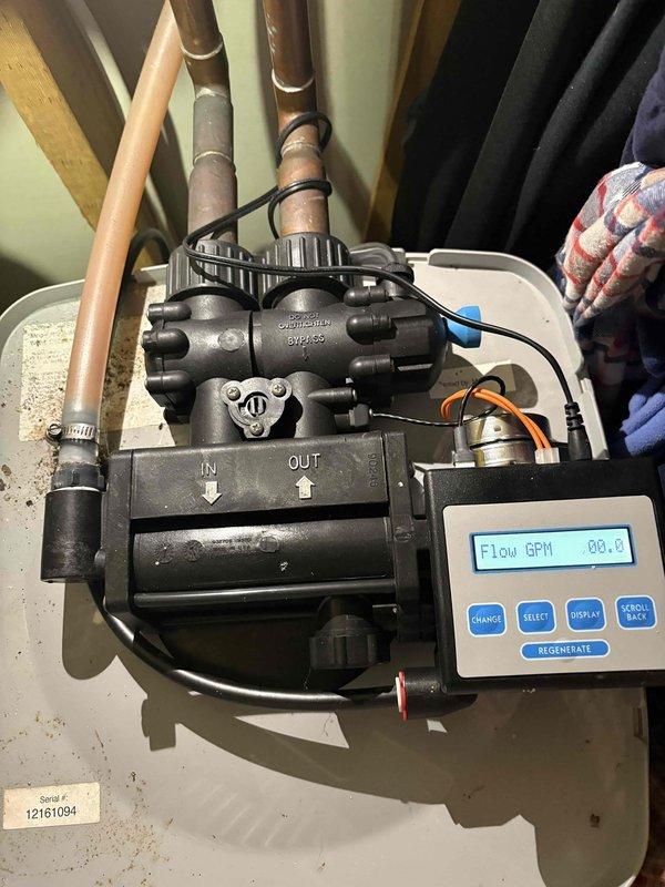 Responded to water softener issue affecting entire home in 35-year-old residence. Upon arrival, inspected plumbing system and identified malfunctioning water softener control unit with digital display showing flow rate and temperature readings. Verified circulation pump operation and checked all copper and PVC pipe connections throughout the mechanical system. Tested regeneration cycle functionality and recalibrated control settings to restore proper water softening operation. Updated customer contact information in system for future service needs. Documented installation with photos showing control panel, flow meter, circulation components, and overall plumbing configuration in basement utility area.