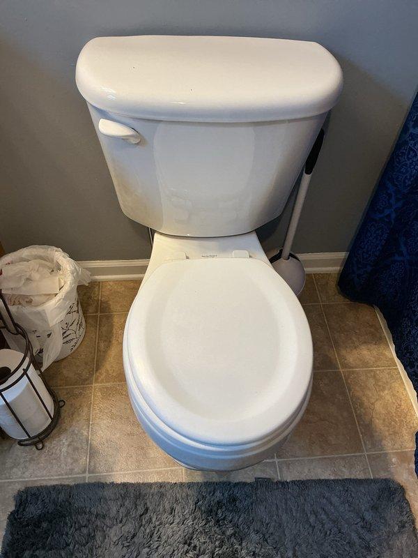 Responded to report of water leaking at base of toilet in residential bathroom. Upon arrival, inspected affected fixture and surrounding area for source of leak. Documented existing conditions with photographs showing standard two-piece white porcelain toilet on tile flooring with visible moisture concerns at base. Assessed wax ring seal integrity and flange connection as probable failure points given age of 19-year-old home and reported ongoing toilet issues. Discussed replacement options for both bathroom fixtures per homeowner request due to chronic performance problems with existing toilets. Provided assessment and recommendations for complete toilet replacement to resolve leaking issue and prevent further water damage to flooring and subfloor.
