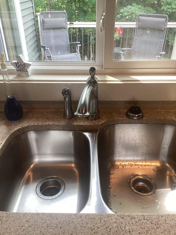 Picked up client-specified faucet from VHC shop per purchase order 784163864-001. Completed faucet replacement on double-basin stainless steel undermount kitchen sink with speckled granite composite countertop. Removed existing faucet assembly and installed new chrome single-handle high-arc faucet with curved spout between basins. Verified proper water flow, checked for leaks at supply line connections, and tested handle operation. Left work area clean with new faucet fully operational.