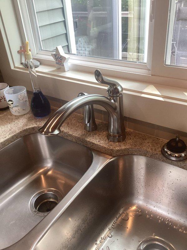 Picked up client-specified faucet from VHC shop per purchase order 784163864-001. Completed faucet replacement on double-basin stainless steel undermount kitchen sink with speckled granite composite countertop. Removed existing faucet assembly and installed new chrome single-handle high-arc faucet with curved spout between basins. Verified proper water flow, checked for leaks at supply line connections, and tested handle operation. Left work area clean with new faucet fully operational.