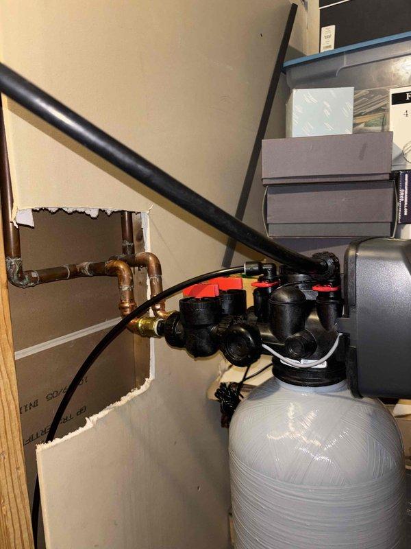 Completed installation of water heater and water softener system in utility room. Installed new water softener unit with digital control head, connected copper supply lines through wall penetration, and configured system controls for proper operation. All plumbing connections secured, system tested and verified operational with no leaks detected.