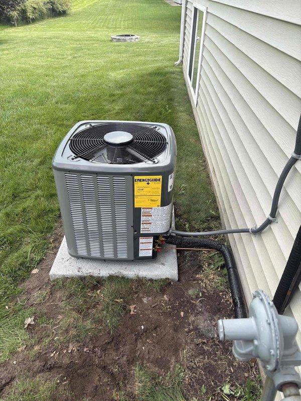 Completed full HVAC system replacement including outdoor condensing unit and indoor air handler components. New condenser installed on concrete pad with proper refrigerant line connections, electrical conduit, and drainage configuration. Indoor furnace and humidifier assembly installed in basement utility area with appropriate PVC condensate drainage system and electrical connections verified per manufacturer specifications.