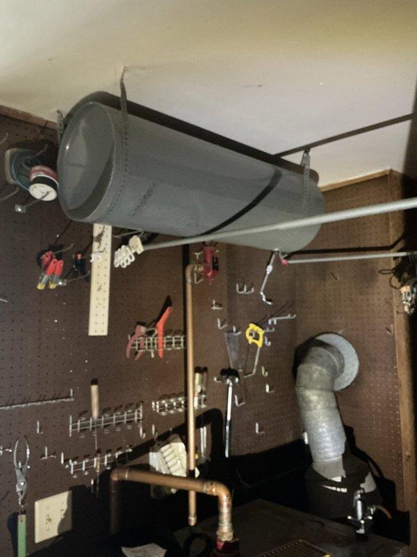 Returned to property to complete estimate assessment for HVAC system work. Documented existing ductwork configuration in garage workshop area, including large gray cylindrical ventilation duct mounted to ceiling and flexible ductwork components. Evaluated electrical connections and control box wiring associated with system. Inspected deteriorated basement utility space showing significant structural damage, including compromised drywall, exposed framing, and damaged concrete flooring. Assessed horizontal ventilation grille component with housing requiring attention. Photographed areas of concern including debris accumulation, material deterioration, and damaged wall sections to support comprehensive estimate preparation for necessary repairs and system modifications.