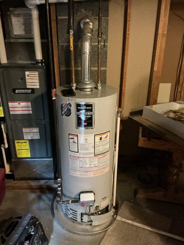 Responded to no hot water complaint on 15-year-old Bradford White water heater. Upon inspection, unit was not producing hot water and had reached end of serviceable life. Documented existing installation with basement utility room setup including gas connections, venting system, and plumbing configuration for replacement recommendations.