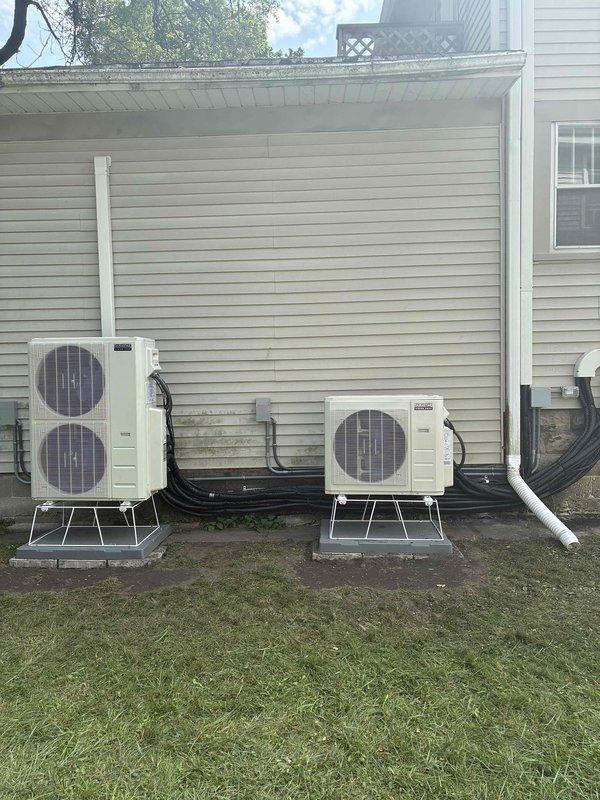Completed full installation of multi-zone ductless mini-split system including three outdoor condenser units mounted on brackets and protective platforms at ground level. Installed refrigerant line sets, electrical conduit, and condensate drain piping connecting outdoor units to indoor air handlers, with all penetrations properly sealed and line sets secured to building exterior. System tested and verified operational with all zones functioning properly.