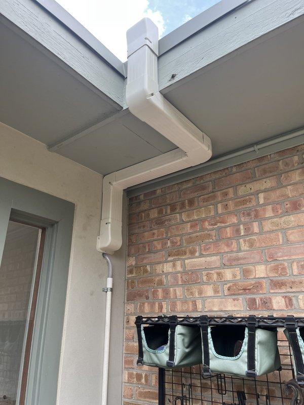 Completed full installation of ductless mini-split system at residential property. Outdoor condenser unit was mounted on reinforced white metal stand with wooden support beams on flat rubber membrane rooftop, positioned near corner of building adjacent to existing gutter and downspout system. Indoor and outdoor units were successfully installed, connected, and tested for proper operation.