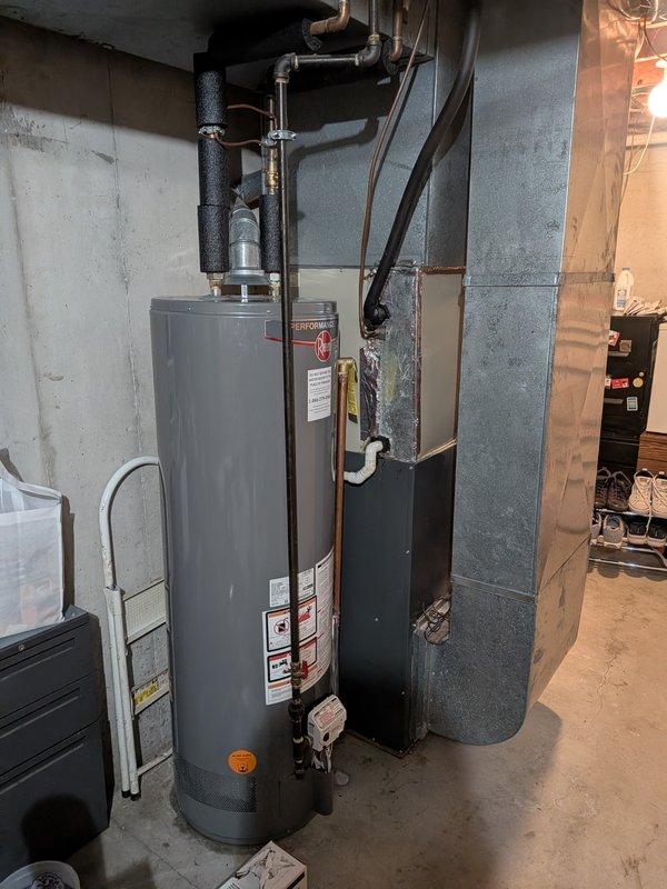 Responded to water leak concern related to air conditioning system. Upon inspection, examined the evaporator unit and surrounding area for moisture issues. Verified the source of the leak and documented the condition of the HVAC equipment and water heater in the mechanical room. The 10-year-old system was assessed, and photographic documentation was captured showing moisture present on the equipment housing and the overall installation configuration in the basement utility area.