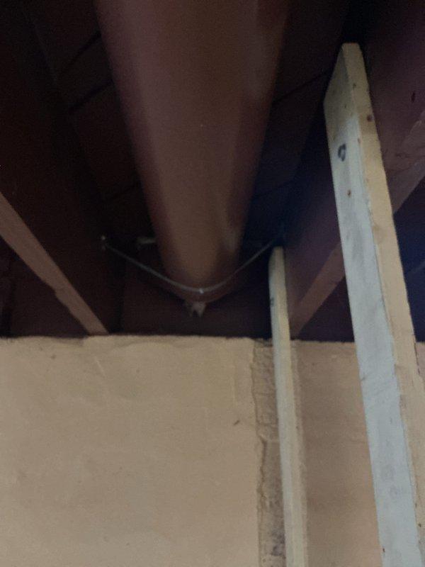 Responded to service call regarding three upstairs vents not connected to the central air conditioning system. Upon inspection, documented the attic space showing exposed HVAC ductwork and structural framing where the disconnected vent runs were located. Also assessed an aging white cast iron radiator in the bathroom that customer requested removal, photographing the unit and surrounding area to document existing conditions including worn carpeting and floor register placement for future work planning.