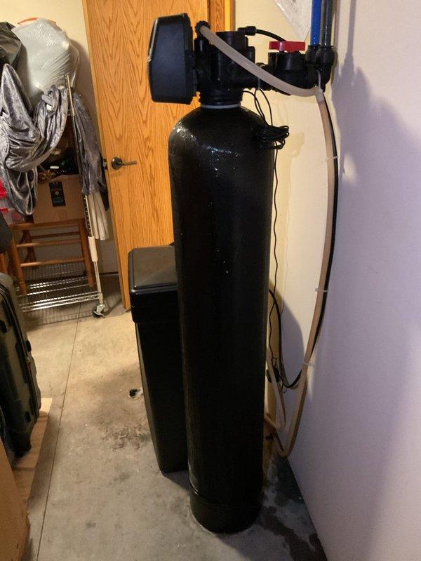 Responded to service call for water leaks affecting multiple plumbing components including water heater, water softener, and well pressure tank. Upon inspection, identified and addressed underlying issues causing moisture problems at connection points between the residential water treatment equipment and pressurized water supply system. Performed diagnostic assessment of the black cylindrical water softener unit with control valve head assembly, white water heater, and turquoise well pressure tank to locate source of leakage. Inspected all plumbing connections, valve fittings, and supply lines throughout the utility room installation. Resolved leak issues through appropriate repairs to affected components and verified proper system operation upon completion.