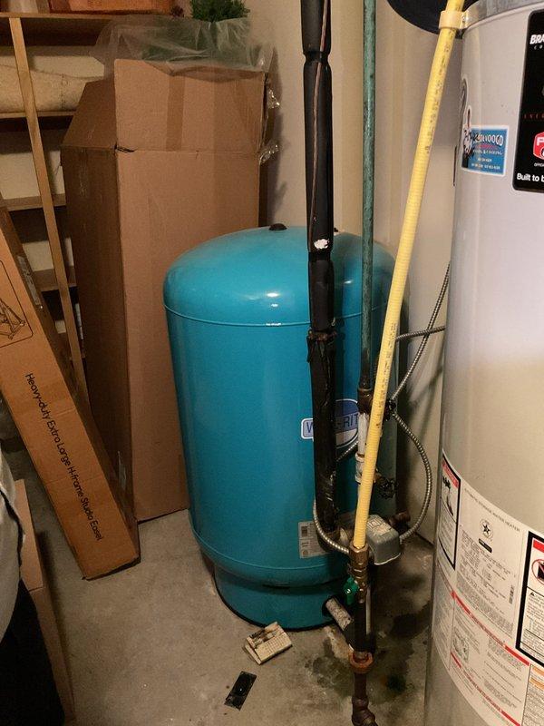 Responded to service call for water leaks affecting multiple plumbing components including water heater, water softener, and well pressure tank. Upon inspection, identified and addressed underlying issues causing moisture problems at connection points between the residential water treatment equipment and pressurized water supply system. Performed diagnostic assessment of the black cylindrical water softener unit with control valve head assembly, white water heater, and turquoise well pressure tank to locate source of leakage. Inspected all plumbing connections, valve fittings, and supply lines throughout the utility room installation. Resolved leak issues through appropriate repairs to affected components and verified proper system operation upon completion.